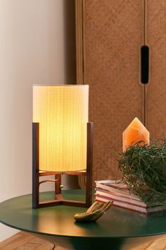 a table with a lamp on top of it next to a pile of books and plants