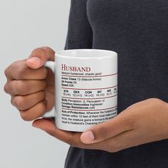 a person holding a white coffee mug in their left hand with the words husband printed on it