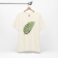 This T-Shirt features an illustration of a nephrolepis exaltata leaf, giving off a trendy and nature-inspired vibe. It is perfect for those who enjoy botanical prints and want to add a touch of greenery to their wardrobe. Ideal for casual wear or as a statement piece for nature lovers. Relevant for Earth Day, nature-themed events, and everyday leisure wear. Product features - 100% Airlume combed and ring-spun cotton - Retail fit for casual and semi-formal settings - Side seams for structural support - Ribbed knit collar with seam for elasticity - Shoulder tape for stability Care instructions - Machine wash: cold (max 30C or 90F) - Non-chlorine: bleach as needed - Tumble dry: low heat - Iron, steam or dry: medium heat - Do not dryclean Nephrolepis Exaltata, Graphic Print Top, Tropical Botanical, Botanical Shirt, Themed Events, Garden Theme, Nature Themed, Plant Lover, Nature Lovers