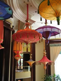 many colorful lamps hanging from the ceiling in a room