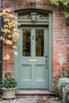 a green front door with potted plants on the side and brick building behind it