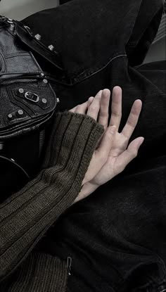 a person's hand resting on top of a black purse