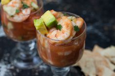 two glasses filled with food and garnish on top of a table