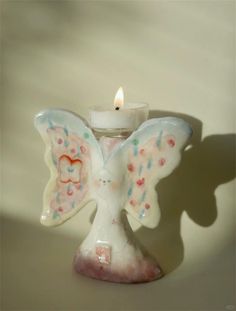 an angel candle holder with a lit candle in it