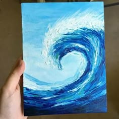 someone is holding up a piece of art that looks like a wave in the ocean