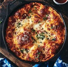 a pizza with cheese and sauce in a pan on a cutting board next to some slices of bread