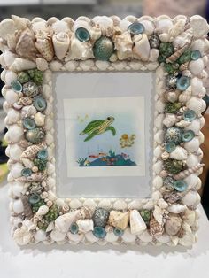 a frame with sea shells and seashells around it on a white table top