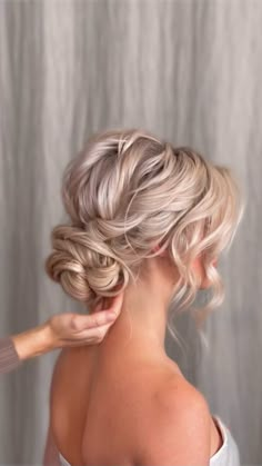 a woman is getting her hair done by another woman in front of a gray background