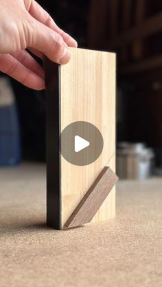 a person holding a wooden block with a video on it