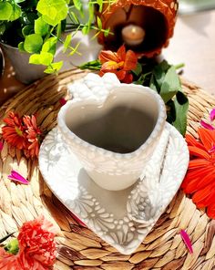 a cup and saucer sitting on top of a wicker tray next to flowers