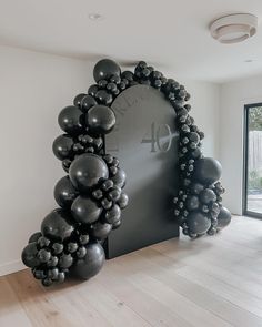 an arch made out of balloons in front of a large clock with the number forty four on it