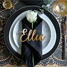 a black and white place setting with a rose on the napkin that says'elu '