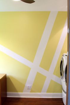 a washer and dryer in a small room with yellow paint on the walls