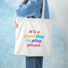 a person holding a tote bag that says it's a good day to play piano