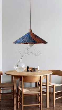 a wooden table and chairs with a blue lamp hanging from the ceiling over it's head