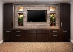 an entertainment center with a flat screen tv mounted on the wall and two planters