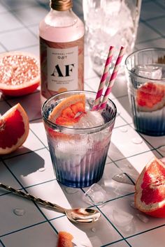 two glasses filled with watermelon and orange slices on top of a tiled table