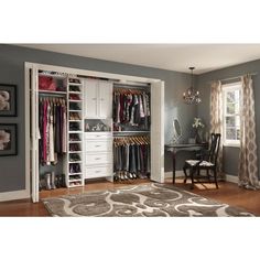 an organized closet with clothes hanging on the doors and drawers, along with a rug in front of it