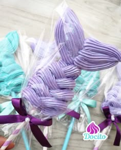 three lollipops wrapped in cellophane with purple and blue ribbons on them