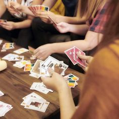 people sitting at a table playing cards with one person reaching for the card in front of them