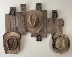 three hats are hanging on the wall with hooks