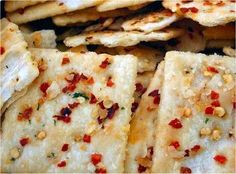 some crackers are stacked up on top of each other with red peppers and seasoning