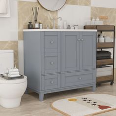 a white toilet sitting next to a blue cabinet in a bathroom on top of a hard wood floor