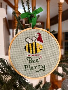 a cross stitch ornament hanging from a christmas tree with the words be merry written on it