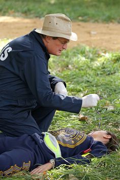 a person laying on the ground with a hat and gloves over their face, holding something in one hand