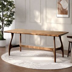 a wooden table sitting on top of a white rug next to a potted plant