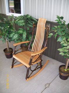 a wooden rocking chair sitting next to a potted plant