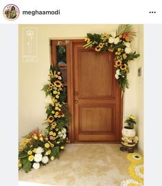 a wooden door decorated with flowers and greenery next to a yellow rug on the floor