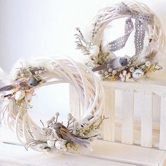 two wreaths sitting on top of a white table next to each other with flowers