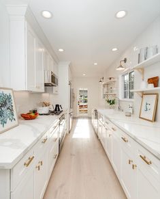 a long narrow kitchen with white cabinets and counter tops