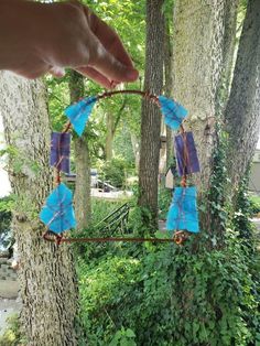 someone is holding an ornament in the shape of a wind chime hanging from a tree