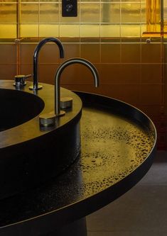 two faucets are sitting on the edge of a round sink in a bathroom