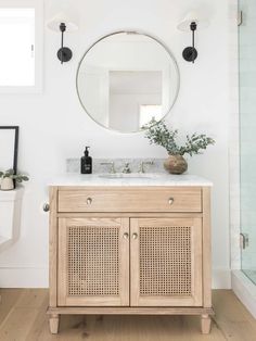 a bathroom vanity with a round mirror above it and a rug on the floor next to it