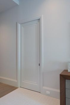 an empty room with a white door and some drawers