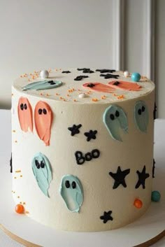 a decorated halloween cake on a white plate with sprinkles and ghost decorations