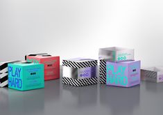 four different colored boxes sitting next to each other on top of a gray surface with white and black stripes