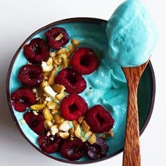 a bowl filled with fruit and ice cream next to a wooden spoon on top of a table