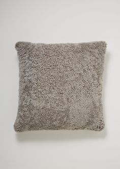 a gray pillow on top of a white wall