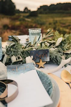 the table is set with greenery and place cards for guests to write their names