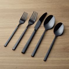 four forks, two spoons and one knife on a wooden table with black handles