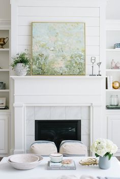 a living room filled with furniture and a painting on the wall above it's fireplace