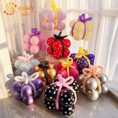 many balloons are arranged on the floor in front of a window with polka dots and bows