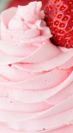 a close up of a cupcake with frosting and a strawberry on the top