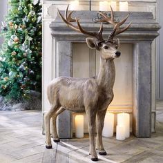 a statue of a deer standing in front of a fireplace next to a christmas tree