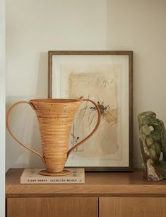 a wooden shelf with a basket and vase on it next to a framed painting in the corner