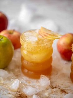 an apple cider with ice and apples in the background